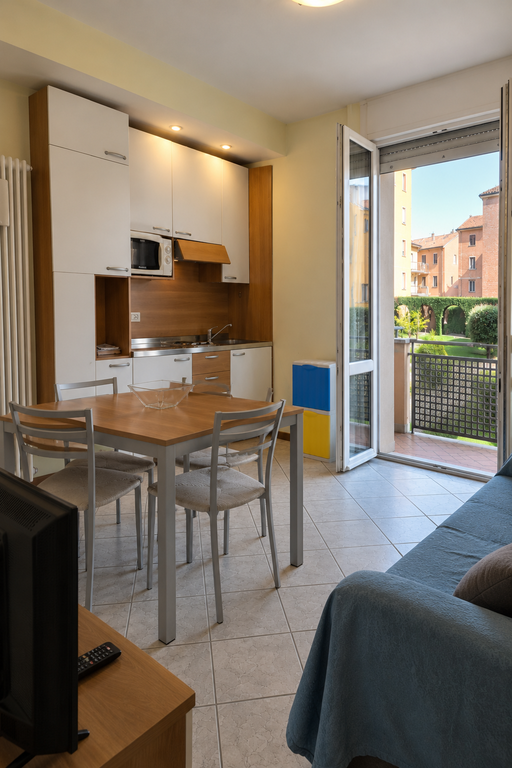 Equipped kitchenette and dining area with upholstered chairs and balcony access at Residence Carracci in Bologna.