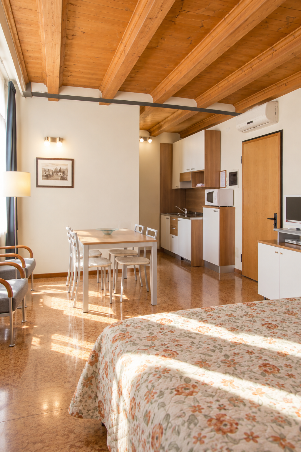 Bright studio apartment with a double bed, kitchenette and dining area at Residence Carracci in Bologna.